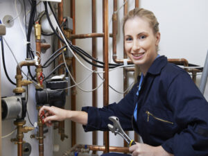 Plumber smiling at camera as she makes pipe repair