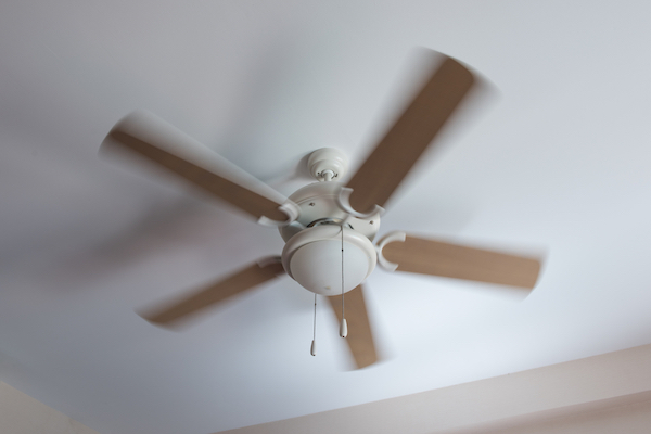 Ceiling fan with wooden blades in a white room
