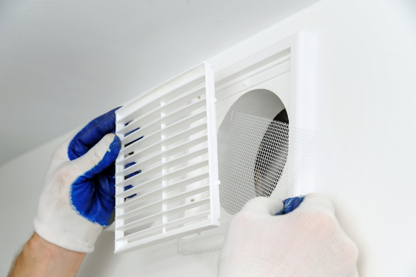 Gloved hands replacing vent grate