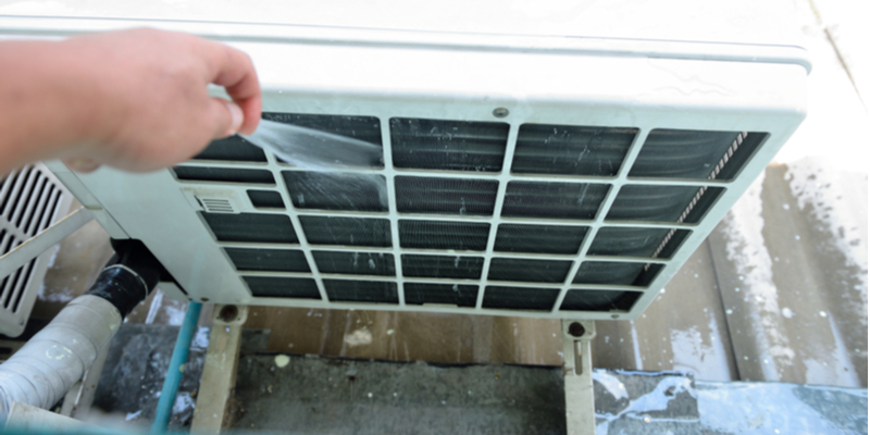 Cleaning out the front of an air conditioner's condenser unit