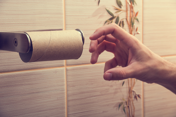 Hand reaching for used-up toilet paper roll