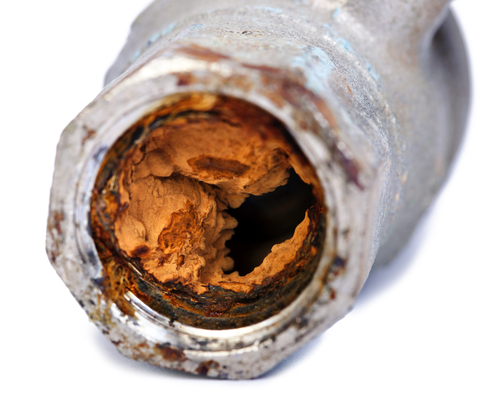 A home pipe filled with orange corrosion.