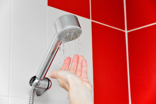 A homeowner puts their hand beneath a light shower trickle.