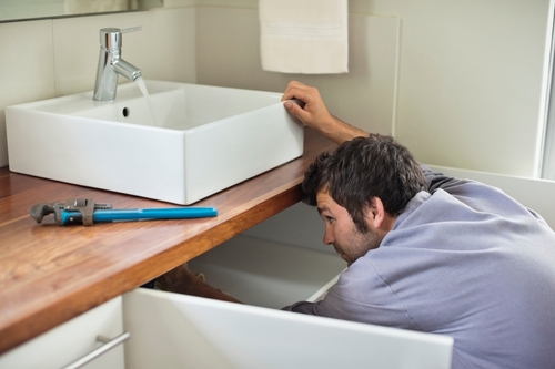 A plumber connects a new bathroom sink.